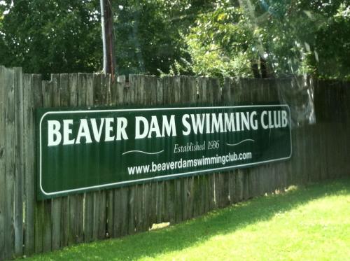Sign for Beaver Dam Swimming Club, established in 1966, displayed on a wooden fence.
