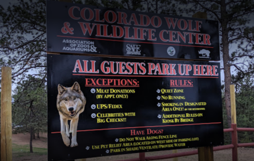 Sign at Colorado Wolf & Wildlife Center detailing parking rules, exceptions, and guidelines for visitors.