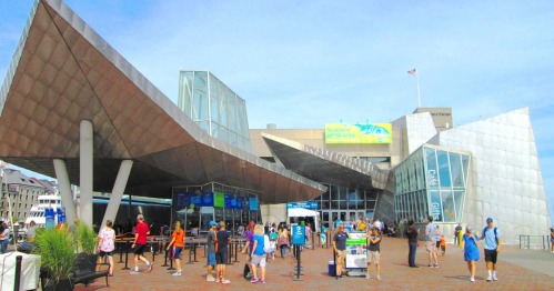 Modern building with angular architecture, bustling with visitors on a sunny day.