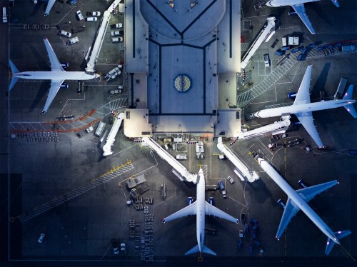 Aerial view of an airport terminal with multiple airplanes and jet bridges connected.
