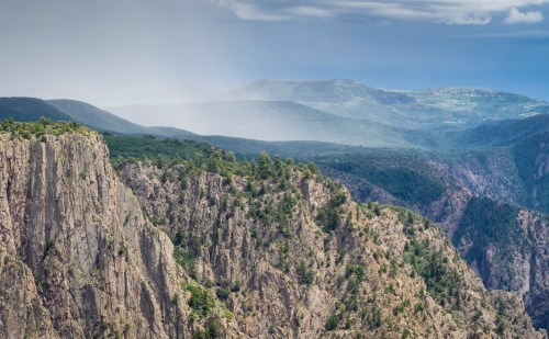 A panoramic view of rugged cliffs and rolling green hills under a cloudy sky.