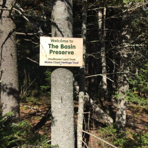 Sign reading "Welcome to The Bessin Preserve" surrounded by trees in a natural setting.