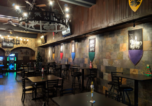 Interior of a themed restaurant with dark wood decor, tables, and colorful banners on the walls.