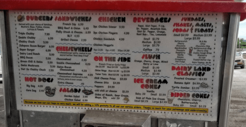 Menu board featuring burgers, sandwiches, chicken, salads, ice cream, and beverages with prices listed.
