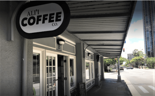 A coffee shop exterior with a sign reading "Ali'i Coffee Co." and a sidewalk view of a city street.