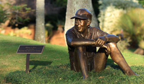 A bronze statue of a smiling man sitting on the grass, with a plaque nearby honoring Edna E. Boyce.