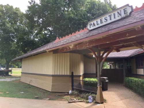 Historic building with a sign reading "Palestine," surrounded by trees and grass.