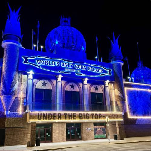 The illuminated Corn Palace in Mitchell, SD, featuring blue lights and a sign reading "World's Only Corn Palace."