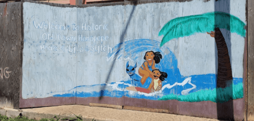 Colorful mural depicting children playing by the water, with palm trees and the text "Welcome to Historic Old Town Hanapepe."