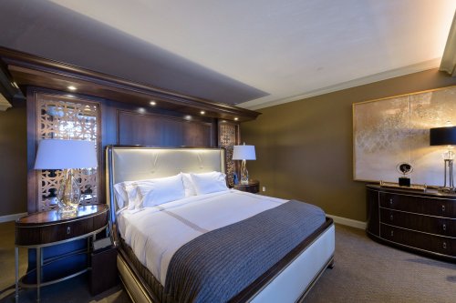 Luxurious hotel bedroom featuring a king-sized bed, elegant decor, and stylish lighting.