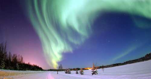 A stunning view of the northern lights illuminating a snowy landscape under a starry sky.