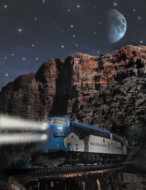 A blue train travels through a rocky landscape under a starry sky and a large moon.
