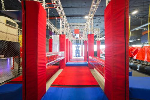 A colorful indoor obstacle course featuring red and blue padded surfaces and climbing structures.