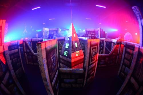 A colorful indoor maze with illuminated walls and a central pyramid, surrounded by vibrant lighting effects.