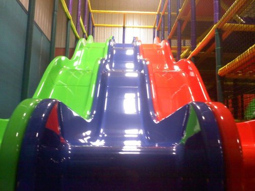 Colorful indoor slides in a play area, featuring green, red, and blue slides.