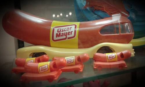 A toy Oscar Mayer Wienermobile with smaller hot dog cars, all featuring the iconic yellow and red branding.