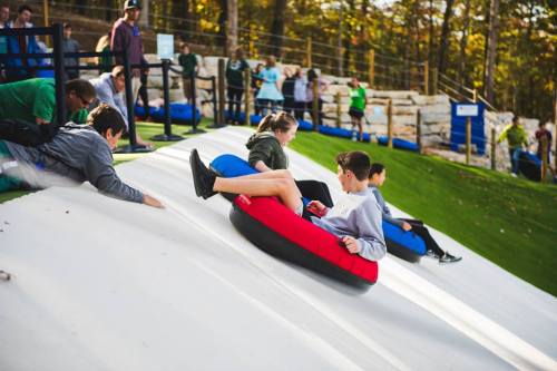 A group of people tubing down a snowy slope, enjoying a fun winter activity in a scenic outdoor setting.