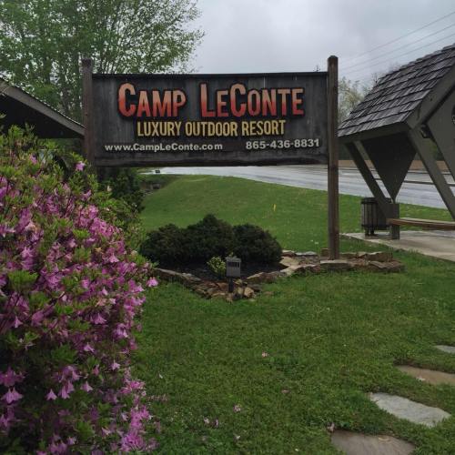 Sign for Camp LeConte, a luxury outdoor resort, surrounded by greenery and blooming flowers.