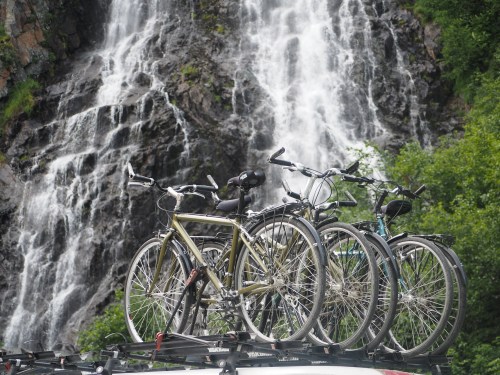 Bicycles on a car rack with a waterfall and lush greenery in the background.