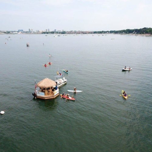 A scenic view of a calm water body with boats and kayaks, featuring a small hut on the shore.