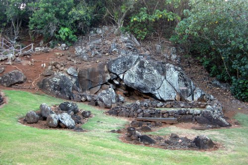 A rocky hillside with large boulders and a grassy area featuring smaller stones arranged in a circular pattern.
