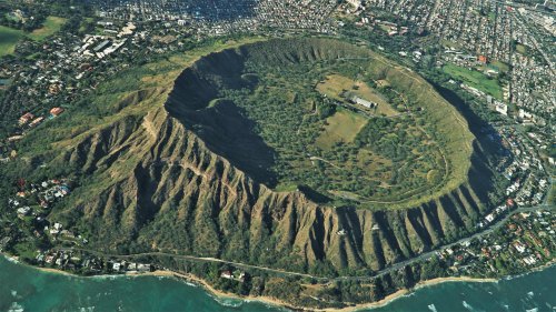 Aerial view of Diamond Head, a volcanic crater in Hawaii, surrounded by lush greenery and urban development.