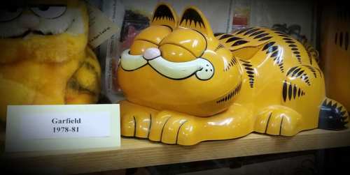 A smiling, orange Garfield figurine lies down, with a label reading "Garfield 1978-81" beside it.