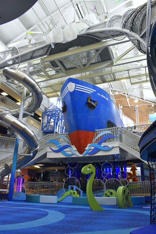 Indoor water park featuring a large blue ship structure and colorful water slides, with playful aquatic decorations.