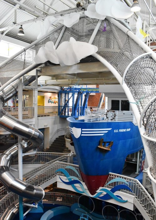 A colorful indoor water park featuring a large ship structure and water slides.