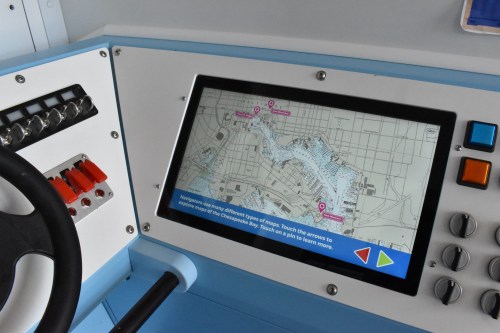 Control panel with a touchscreen displaying a map and navigation options, featuring buttons and levers.
