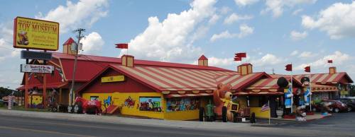 Colorful exterior of a toy museum with a striped roof, flags, and playful decorations, set against a blue sky.