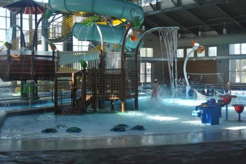 Indoor water park featuring slides, play structures, and water features with children playing in the pool area.