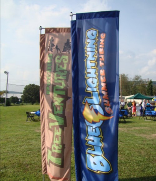 Two tall banners on a grassy field: one for "TreeVentures" and the other for "Blue Lightning Shimmer Tubing."