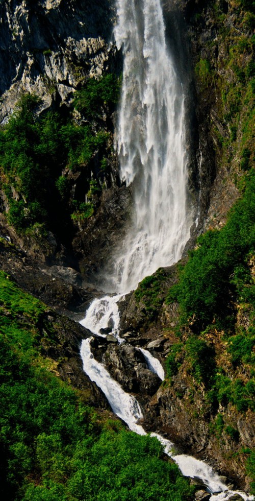A stunning waterfall cascading down rocky cliffs, surrounded by lush green vegetation.