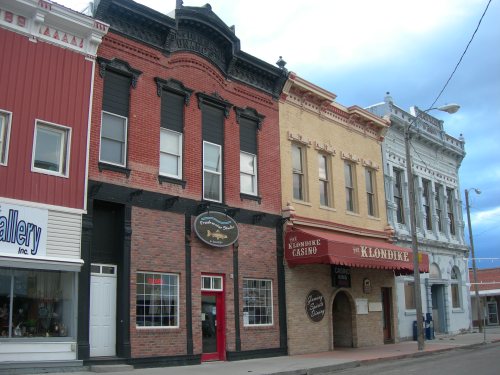 Historic buildings with colorful facades, featuring shops and a restaurant named "The Klondike."