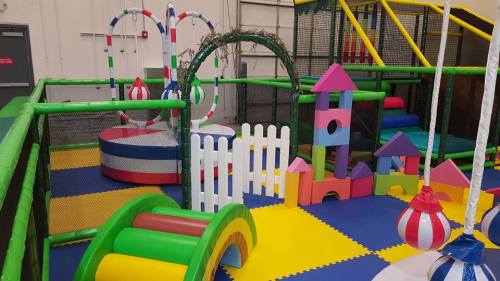 Colorful indoor playground with various structures, including slides, climbing areas, and soft play equipment.