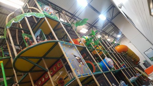 A colorful indoor play structure with slides, climbing areas, and themed decorations for children.