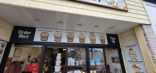 A storefront with a menu displaying various popcorn flavors and a sign for ordering and pickup.