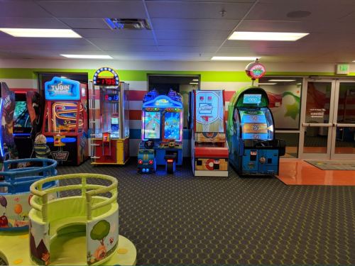 A colorful arcade with various game machines and a play area, featuring bright lights and vibrant decor.