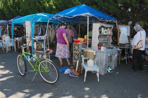 A vibrant outdoor market scene with tents, vintage items for sale, and a green bicycle parked nearby.