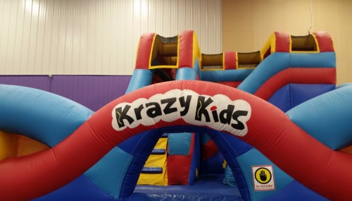 Colorful inflatable play structure with slides and a "Krazy Kids" sign. Perfect for children's entertainment.