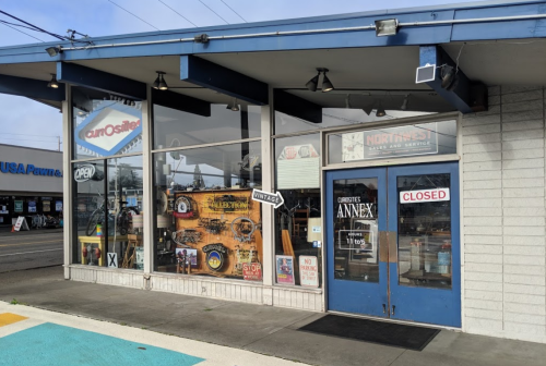 A storefront with a blue awning, featuring "OPEN" and "CLOSED" signs, and vintage decor in the windows.