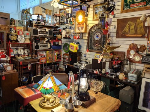 A cozy antique shop filled with vintage items, including lamps, clocks, and decor, creating a nostalgic atmosphere.