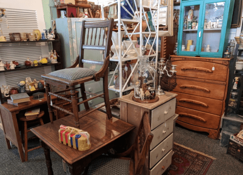 A cozy antique shop filled with various vintage furniture pieces, including chairs, cabinets, and decorative items.