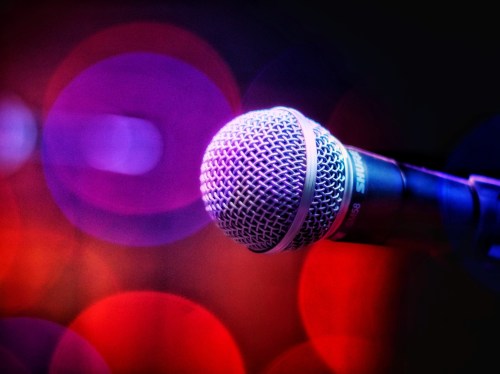Close-up of a microphone with a blurred, colorful background of purple and red lights.