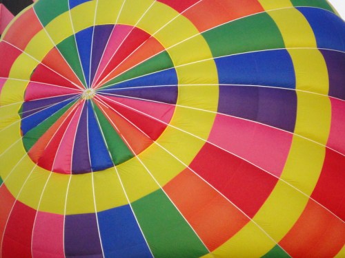 Colorful circular pattern of a hot air balloon canopy, featuring vibrant segments in red, yellow, green, and blue.