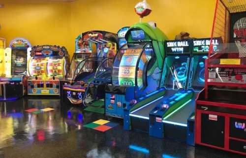 A colorful arcade filled with various games, including skee-ball and ticket redemption machines, against a bright yellow wall.