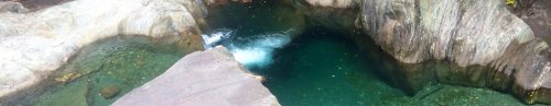 A serene natural pool surrounded by rocky formations, with clear turquoise water and gentle ripples.