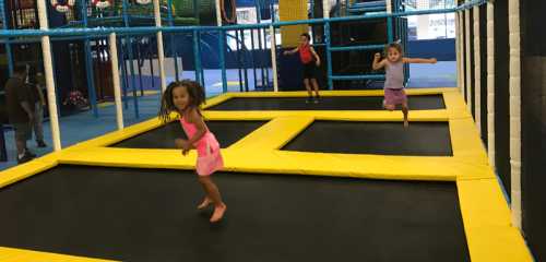 Children jumping on trampolines in a colorful indoor play area.