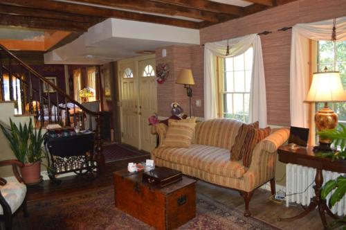 Cozy living room with a striped sofa, wooden beams, and warm lighting, featuring plants and a vintage trunk.